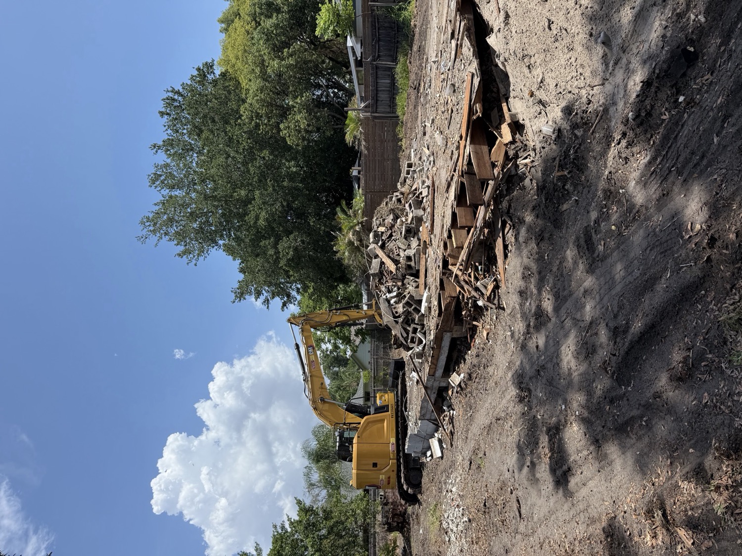 Brightview demolition in progress, excavator and separated debris on a cleared Central Florida lot